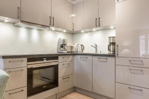 uma cozinha com armários brancos e um lavatório em Haus Mateika Whg 7 em Westerland