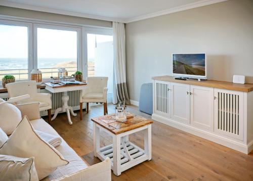 a living room with a couch and a table with a tv at Seafront Duenenhof zum Kronprinzen in Wenningstedt