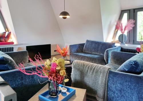 a living room with blue couches and a vase with flowers at Landhaus Braderup in Braderup