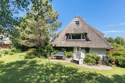 a thatch roofed house with a patio and a yard at Landhaus Braderup in Braderup