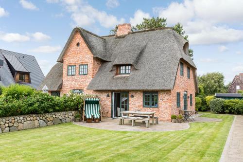 een oud huis met een rieten dak en een picknicktafel bij Watthues Wenningstedt in Wenningstedt