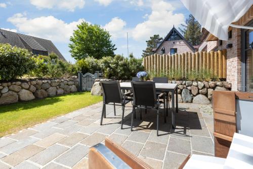 een patio met een tafel en stoelen in een tuin bij Vinhues in Westerland