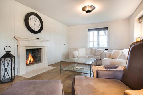 a living room with a fireplace and a clock on the wall at Hiirhues in Braderup