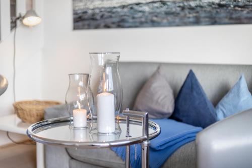 a glass table with candles and a couch at Wattblick in Munkmarsch