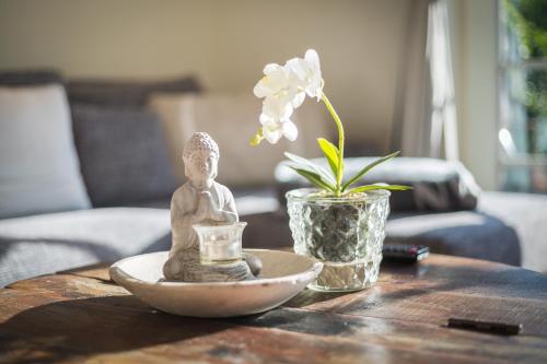 einen Tisch mit einer Figur und eine Vase mit einer Blume in der Unterkunft Heide Hüs in Munkmarsch
