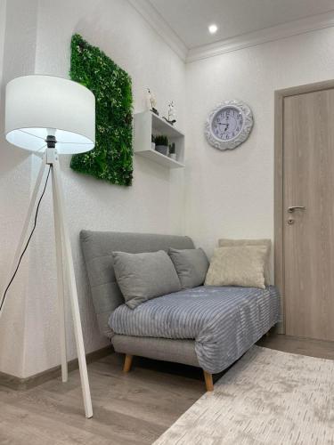 a couch in a living room with a lamp and a clock at Apartmani Porodica Karalić Vlašić in Vlasic