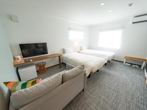 a hotel room with two beds and a couch at AIR FURANO in Furano