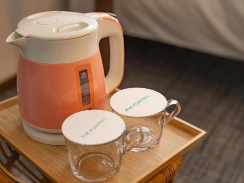 an orange kettle and two cups on a wooden tray at AIR FURANO in Furano