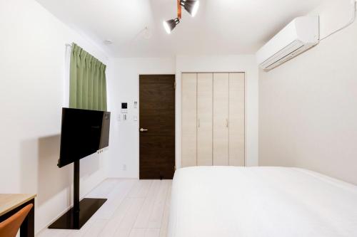 a bedroom with a bed and a flat screen tv at FL Residence Jingu Gyoen IV in Tokyo