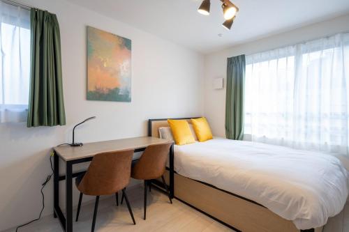 a bedroom with a bed and a desk with two chairs at FL Residence Jingu Gyoen IV in Tokyo