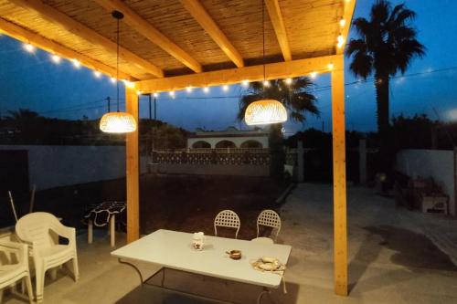 un patio con tavolo, sedie e luci di Casa Vacanza Villa Stefy - Salento a Torre Chianca
