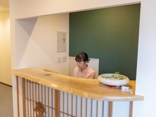 a woman standing behind a counter in a room at AIR FURANO in Furano