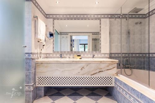 Pine Cliffs Suites في ألبوفيرا: حمام مع حوض كبير ومرآة