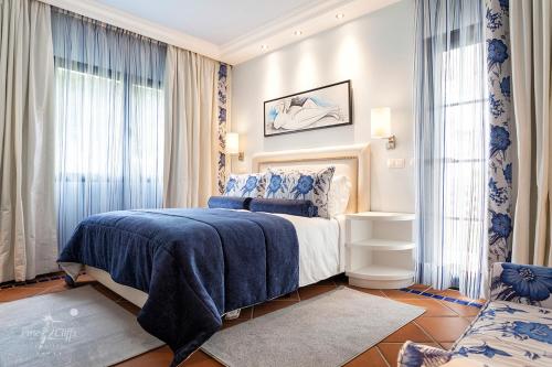 Pine Cliffs Suites في ألبوفيرا: غرفة نوم بها سرير ونوافذ زرقاء وبيضاء