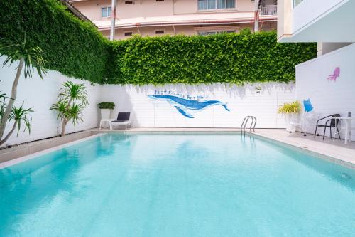 uma piscina ao lado de uma parede branca com plantas em Royal Pavilion Hua Hin em Hua Hin