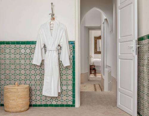 a robe hanging on a wall in a bathroom at Riad L'Hôtel Marrakech in Marrakesh