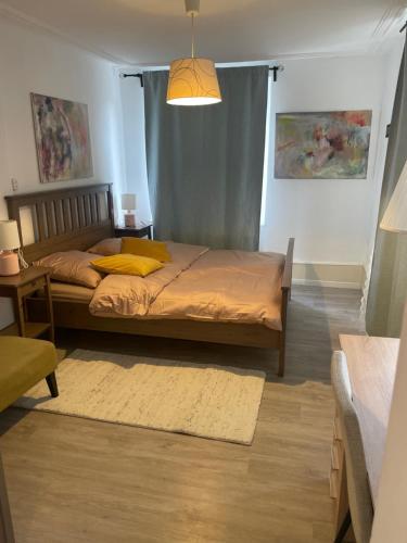 een slaapkamer met een bed met een geel kussen erop bij Le MONOT Residence in Bazel