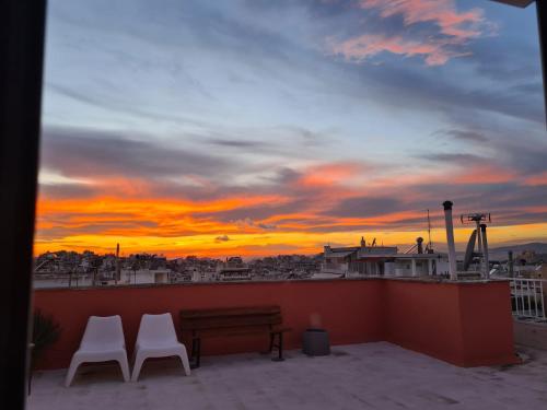 - deux chaises et un banc sur un balcon avec un coucher de soleil dans l'établissement Eagle's Nest, à Athènes