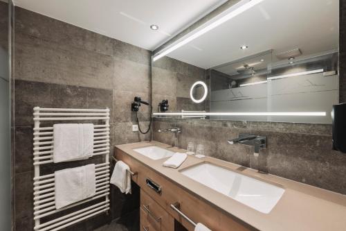 a bathroom with a sink and a large mirror at Hotel Piz Buin in Ischgl