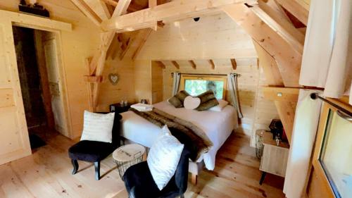 ein Schlafzimmer in einem Blockhaus mit einem Bett und Stühlen in der Unterkunft Cabane perchée luxe avec jacuzzi Domaine du Marais Maisse in Maisse