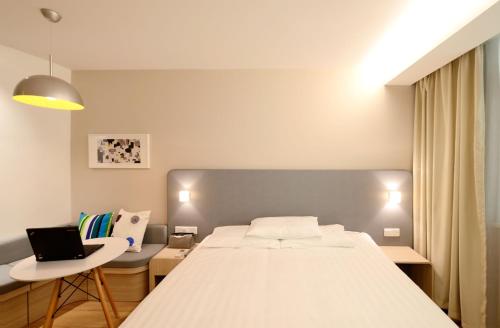 1 dormitorio con cama y mesa con ordenador portátil en CHAMBRES DANS CHARMANTE MAISON ALSACIENNE, en Herrlisheim