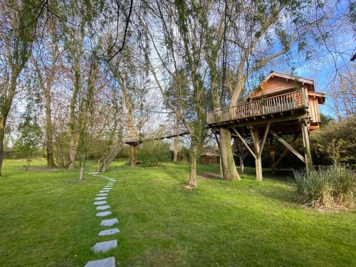 una casa en el árbol en un campo con una pasarela en Cabane perchée luxe avec jacuzzi Domaine du Marais Maisse, en Maisse