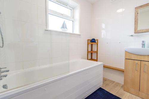 een witte badkamer met een bad en een wastafel bij Little Hotsie in Southwold