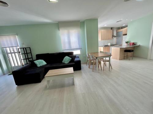 ein Wohnzimmer mit einem schwarzen Sofa und einem Tisch in der Unterkunft Barrio San Miguel Más que apartamentos in Murcia