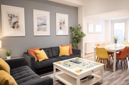 a living room with a couch and a table at 8 Bed, comfortably sleeps 10, 3 Bath house, 5 Mins Manchester Centre in Manchester
