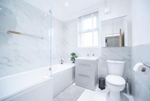 a white bathroom with a toilet and a tub and a sink at 8 Bed, comfortably sleeps 10, 3 Bath house, 5 Mins Manchester Centre in Manchester