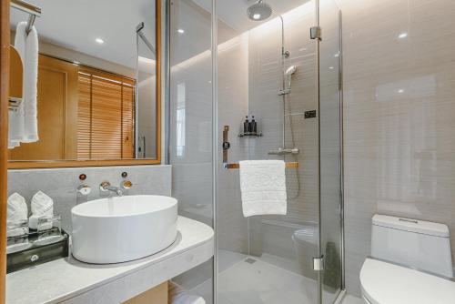 biała łazienka z umywalką i prysznicem w obiekcie Wenzhou Hangbin International Hotel w mieście Wenzhou
