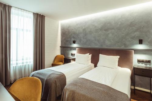 a hotel room with two beds and a desk at Konventa Sēta Hotel Keystone Collection in Riga