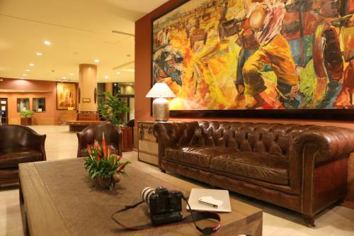 a living room with a brown leather couch and a large painting at Hotel Memling in Kinshasa
