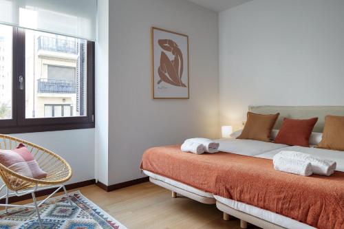 een slaapkamer met een bed, een stoel en een raam bij Eiffel - The Rentals Collection in San Sebastian