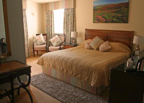 a bedroom with a bed and a chair and a window at The Crown Hotel in Exford