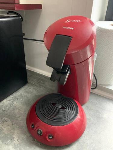 Une machine rouge est installée à côté d'un réfrigérateur. dans l'établissement Maison proche centre-ville 4 personnes 2 chambres, à Amiens