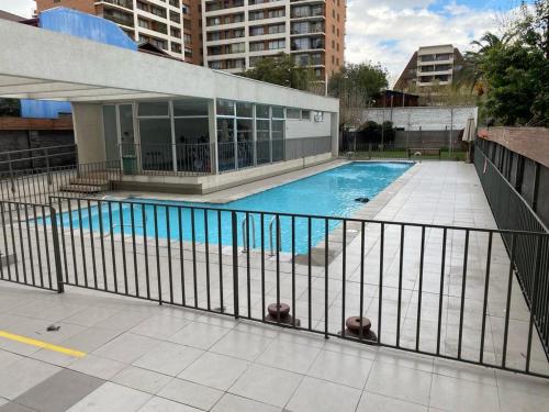 une piscine derrière une clôture dans un bâtiment dans l'établissement Ñuñoa, Bello departamento, La mejor ubicacion, à Santiago