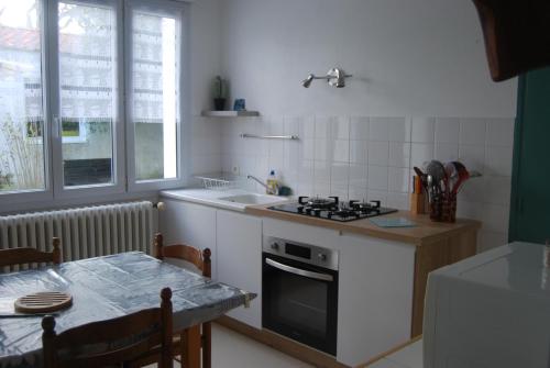 a kitchen with a stove and a sink and a table at Vaiana in Beauvoir-sur-Mer