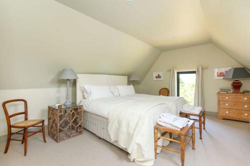 a bedroom with a large bed and two chairs at Duckpitts Barn in Canterbury