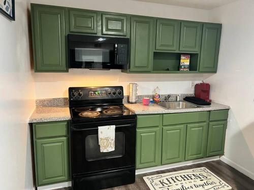 a green kitchen with a stove and a sink at Cozy 2BED 6min EWR NYC DTWN in Newark