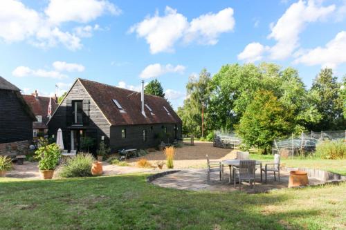 a farmhouse with a table and chairs in a yard at Duckpitts Barn in Canterbury