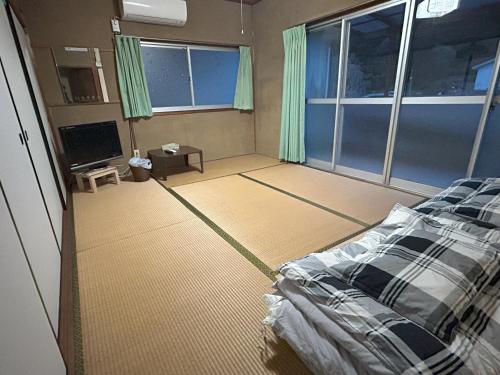 pusty pokój z łóżkiem i telewizorem w obiekcie 北房まちの駅 AZAE ドリトミー azae w mieście Maniwa