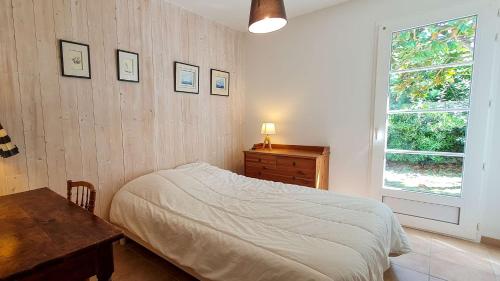 une chambre avec un lit, une table et une fenêtre dans l'établissement Dans le centre du village de La Couarde, charmante ville de plain pied, à La Couarde-sur-Mer