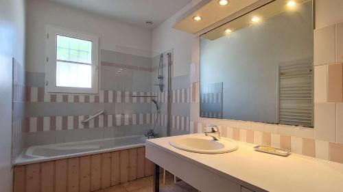 une salle de bain avec un lavabo, une baignoire et un miroir dans l'établissement Dans le centre du village de La Couarde, charmante ville de plain pied, à La Couarde-sur-Mer