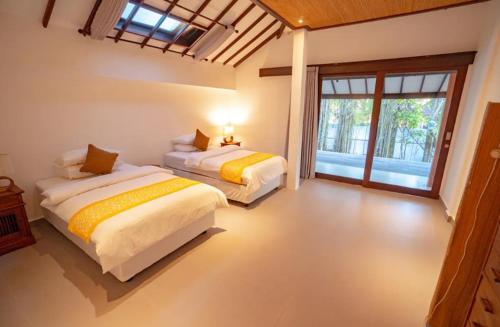 a bedroom with two beds and a large window at Villa Jado 2 - 3 Bedroom Villa With Private Pool in Kerobokan
