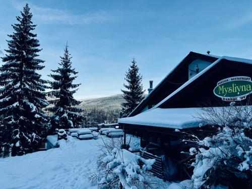 domek narciarski z śniegiem na dachu i drzewami w obiekcie Myslivna Harrachov w mieście Harrachov