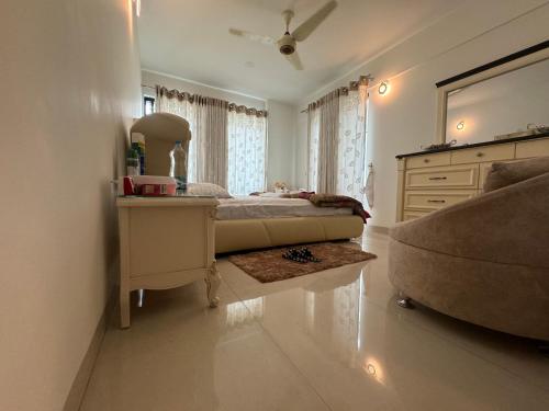 een slaapkamer met een bed, een dressoir en een bank bij Hibiscus Apartments in Dhaka