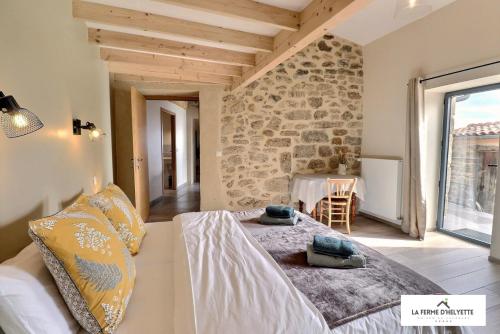 Cama grande en habitación con pared de piedra en La Ferme d' Helyette, en Toulaud