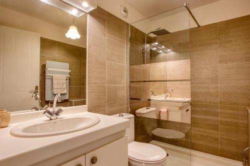 une salle de bain avec un lavabo, des toilettes et un miroir dans l'établissement Cocoon Drive - Climatisé avec piscine partagée, à Saint-Raphaël