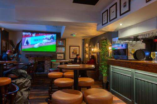 um bar com bancos e uma televisão num bar em The Crown & Anchor em Manchester